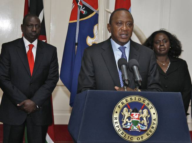 In this photo released by Kenya's Presidency, Kenyan President Uhuru Kenyatta, center, flanked by Deputy President William Ruto, left, and other senior Government and Security officials, makes a television address to the nation from State House in Nairobi, Kenya, Tuesday, Sept. 24, 2013.