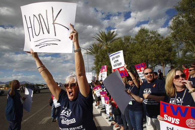 Union member Patti Phillips raises a sign as she joins over 300 members of the Transit Workers Union, in town for their convention, in a picket outside of Allegiant Air headquarters Thursday, Sept. 26, 2013. The union members were trying to raise awareness of Allegiant's customer service record as well as their inability to reach a labor agreement with more than 600 of their flight attendants.