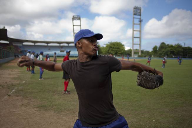 A baseball player who plays for the Cuban baseball team Industriales, winds up to throw a ball during a training session in Havana, Cuba, Friday, Sept. 27, 2013. Cuba announced Friday that its athletes will be allowed to sign contracts to compete in foreign leagues, a shift from decades of policy that held professional sports to be anathema to socialist ideals.
