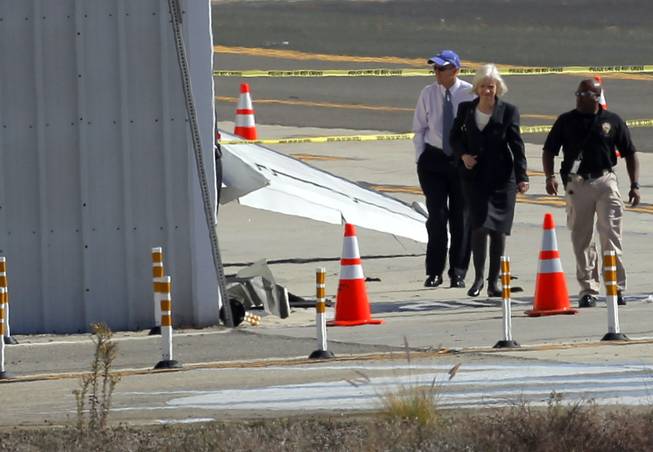 Investigators stand near a hanger at the site of a plane crash in Santa Monica, Calif. Monday, Sept 30, 2013. Investigators awaited the arrival of a crane Monday at a Southern California airport where a private jet crashed into a hangar after landing, but they did not expect to find any survivors on the flight from Idaho, officials said.