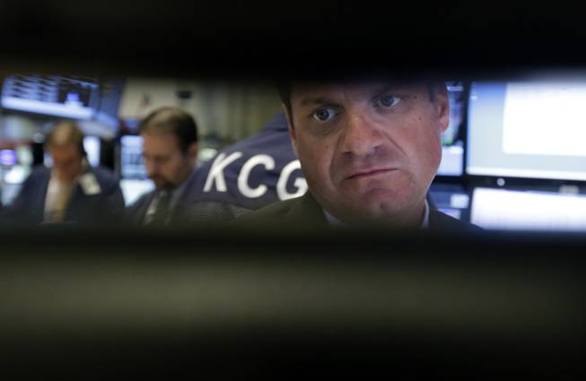 Specialist Michael Guli, right, is framed by his monitors as he works at his post on the floor of the New York Stock Exchange Wednesday, Sept. 18, 2013. Stocks were little changed in early trading Wednesday as investors wait to hear from the Federal Reserve on the fate of the central bank's bond-buying program.