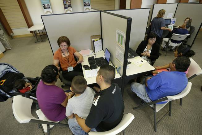 Carol Stuewe, top left, a volunteer counselor with Insure Central Texas explains health insurance options to Eric Sosa and Nancy Maldonado, Tuesday, Oct. 1, 2013, in Austin, Texas. Texas hospitals, clinics and charities are gearing up to help uninsured Texans enroll in health care exchanges after Gov. Rick Perry declared the state government would do as little as possible to help implement the Affordable Care Act.