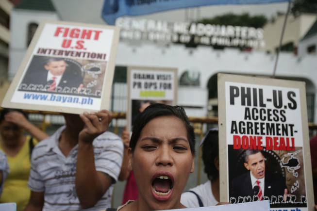 A Filipino protester shouts slogans with pictures of U.S. President Barack Obama during a rally outside the Camp Aguinaldo military headquarters in suburban Quezon city, north of Manila, Philippines on Tuesday Oct. 1, 2013. The group opposed current negotiations to have larger U.S. military presence in the country. They are preparing for more protests in time for the planned visit of Obama this month.