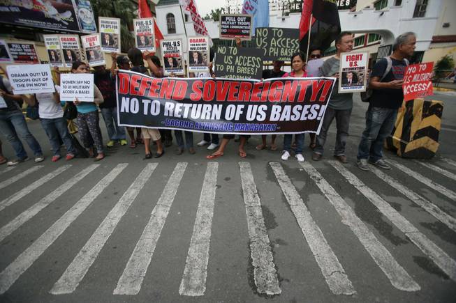 Filipino protesters hold slogans as they stage a rally outside the Camp Aguinaldo military headquarters in suburban Quezon city, north of Manila, Philippines on Tuesday Oct. 1, 2013. The group opposed current negotiations to have larger U.S. military presence in the country. They are preparing for more protests in time for the planned visit of U.S. President Barack Obama this month.