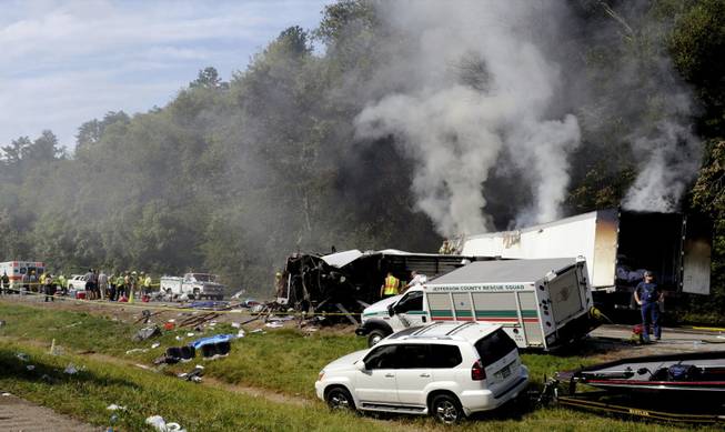 Emergency personnel search the scene near a collision involving a bus on I-40, in Dandridge, Tenn, on Wednesday, Oct. 2, 2013. A spokeswoman for Tennessee's Safety Department says there are multiple fatalities and injuries in an interstate bus crash between a passenger bus, a tractor-trailer and another vehicle.