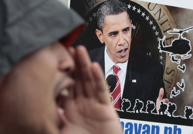 A Filipino protester shouts slogans in front of a picture of U.S. President Barack Obama during a rally outside the Camp Aguinaldo military headquarters in suburban Quezon city, north of Manila, Philippines on Tuesday Oct. 1, 2013. The group opposed current negotiations to have larger U.S. military presence in the country. They are preparing for more protests in time for the planned visit of Obama this month.