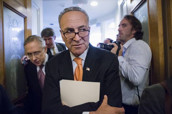 Sen. Charles Schumer, D-N.Y., center, and Senate Majority Leader Harry Reid of Nev., left, make their way through a crush of reporters on Capitol Hill in Washington, Wednesday, Oct. 2, 2013, after announcing to reporters that President Barack Obama has invited the top leaders in Congress to meet with him at the White House to seek a solution to the government shutdown crisis. A funding cutoff for much of the government began Tuesday as a Republican effort to kill or delay the nation's health care law stalled action on a short-term, traditionally routine spending bill. Lawmakers in both parties have ominously suggested the partial shutdown might last for weeks. (AP Photo/J. Scott Applewhite)