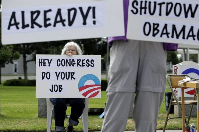 Nelly Mathov, 79, holds a sign while protesting against the government shutdown outside the federal building in Los Angeles on Wednesday, Oct. 2, 2013. President Barack Obama summoned congressional leaders to the White House on the second day of a partial government shutdown that has furloughed hundreds of thousands of workers and closed military cemeteries as far away as France. (AP Photo/Jae C. Hong)
