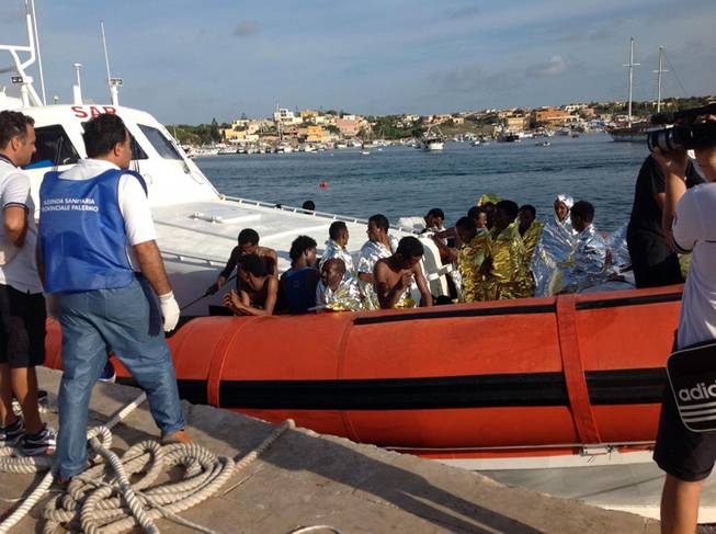 An Italian coast guard boat carry rescued migrants as they arrive in the port of Lampedusa Thursday, Oct. 3, 2013. A ship carrying African migrants to Europe caught fire and capsized off the Italian island of Lampedusa on Thursday, killing at least 94 people as it spilled hundreds of passengers into the sea, officials said.