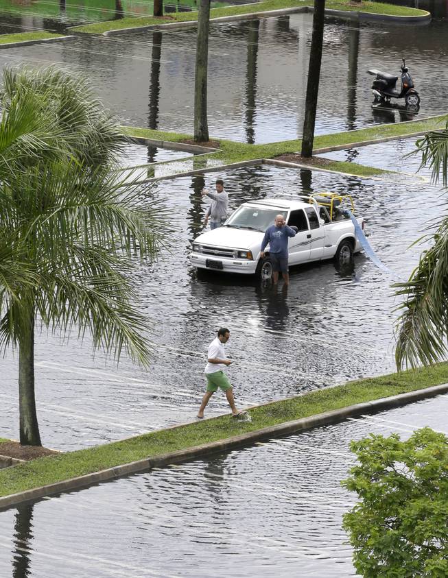 Workers pump water from the parking lot of the Dadeland Plaza shopping center, Thursday, Oct. 3, 2013, after heavy rains in Pinecrest, Fla., a suburb of Miami. Preparations began Thursday along the central Gulf Coast as newly formed Tropical Storm Karen threatened to become the first named tropical system to menace the United States this year.