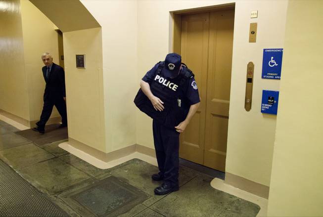 Sen. Jack Reed, D-R.I. watches at left as a Capitol Hill police officer puts on a his body armor after a reported shooting on Capitol Hill in Washington, Thursday, Oct. 3, 2013. A police officer was reported injured after gunshots at the U.S. Capitol, police said Thursday. They locked down the entire complex, at least temporarily derailing debate over how to end a government shutdown.