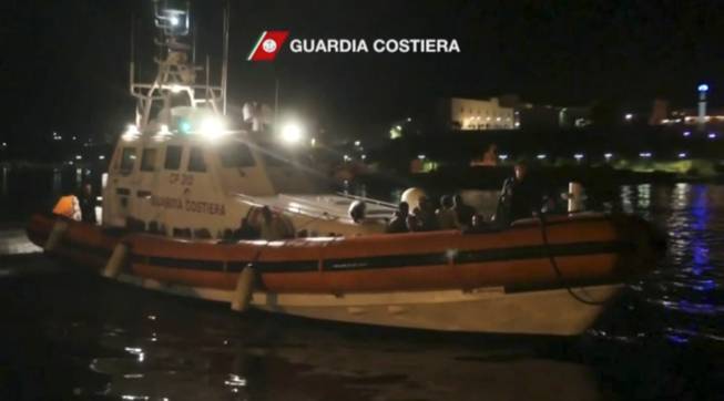 In this image made from video provided by the Italian Coast Guard, an Italian Coast Guard vessel transporting survivors of a ship carrying migrants which caught fire and sank off the Sicilian island of Lampedusa, arrives into port on the island of Lampedusa, Italy, Thursday, Oct. 3, 2013.