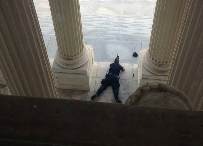A U.S. Capitol police officer lies on the steps of the Senate with a gun drawn in response to a report of shots fired Thursday, Oct. 3, 2012. A police officer was reported injured after gunshots at the U.S. Capitol. They locked down the entire complex, at least temporarily derailing debate over how to end a government shutdown.