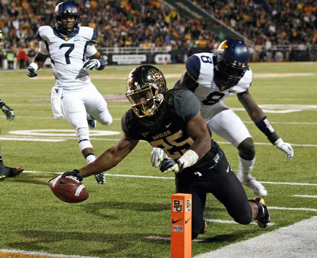 In this Oct. 5, 2013, file photo, Baylor running back Lache Seastrunk (25) scores past West Virginia safety Karl Joseph (8) during the first half of an NCAA college football game in Waco, Texas. Seastrunk boldly stated last year that he would win the 2013 Heisman Trophy, or come very close. Through four games, the former Oregon transfer is the nation's second-leading rusher in the 15th-ranked Bears' high-scoring offense.
