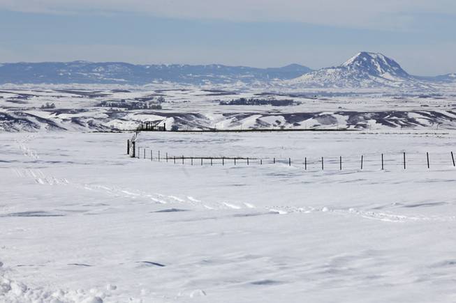 In this Monday, Oct. 7, 2013, file photo, snowmobile tracks can be seen in the snow between fence lines and Highway 34 east of Sturgis, S.D., as area ranchers race to find cattle that drifted beyond fenced pastures during the blizzard. Western South Dakota ranchers are reeling from the loss of tens of thousands of cattle in last weekends blizzard as pits to dispose of the dead animals are set to open Monday, Oct. 14, 2013.