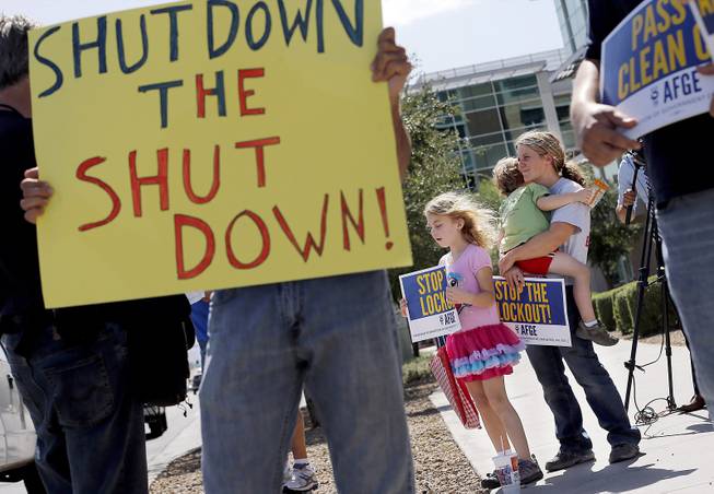 As the federal government shutdown continues, Tory Anderson, right, with her kids Audrey, 7, and Kai, 3, of Goodyear, Ariz., join others as they rally for the Alliance of Retired Americans to end the shutdown in front of the Social Security Administration offices on Wednesday, Oct. 9, 2013, in Phoenix.