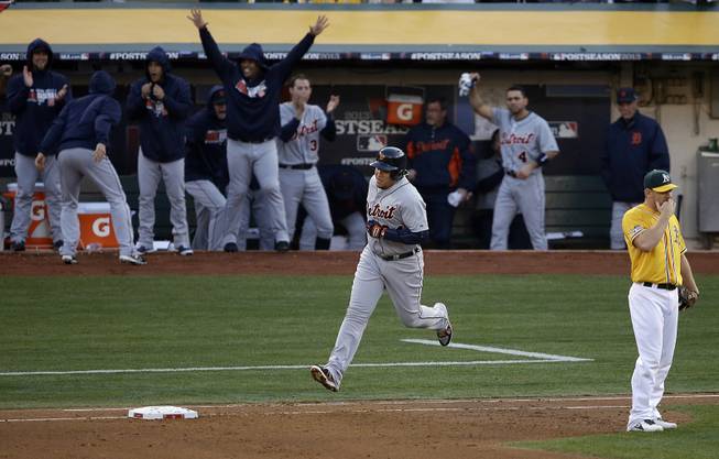The Detroit Tigers dugout celebrates as Miguel Cabrera, center, rounds the bases after hitting a two-run home run off Oakland Athletics pitcher Sonny Gray during the fourth inning of Game 5 of an American League baseball division series in Oakland, Calif., Thursday, Oct. 10, 2013. Athletics first baseman Brandon Moss, right, reacts.