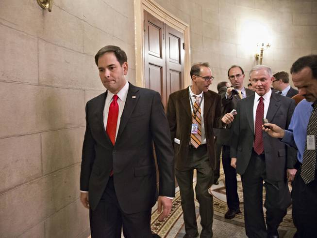 Sen. Marco Rubio, R-Fla. passes at left as Sen. Jeff Sessions, R-Ala., right, talks with reporters on Capitol Hill in Washington, Friday, Oct. 11, 2013, as Republican returned to the Capitol after a two-hour meeting at the White House with President Barack Obama, trying to come up with a bipartisan solution to the budget stalemate.