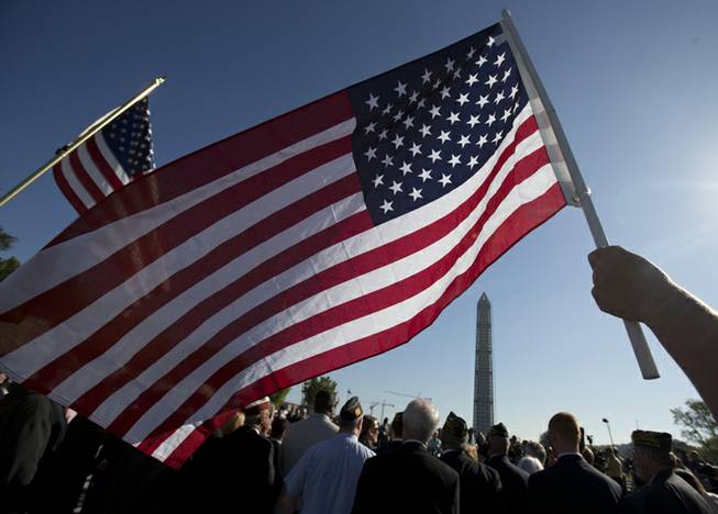 US Marine Terri Shreiner holds an American flag during a rally at the National World War II Memorial, Tuesday, Oct. 15, 2013, in Washington, by the Military Coalition, a coalition of 33 of the leading veterans and uniformed services organizations, to demand an end to the partial government shutdown.The federal government remains partially shut down and faces a first-ever default between Oct. 17 and the end of the month. The Washington Monument is seen in the background.