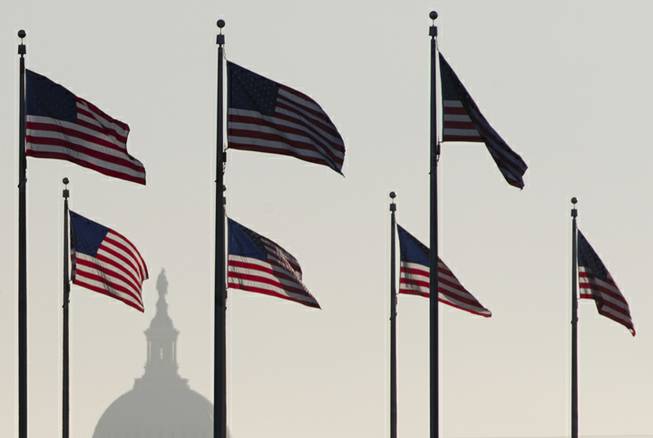 The US Capitol Dome is seen in the distance as American flags fly on the National Mall around the base of the Washington Monument, Tuesday, Oct. 15, 2013, in Washington. The federal government remains partially shut down and faces a first-ever default between Oct. 17 and the end of the month.