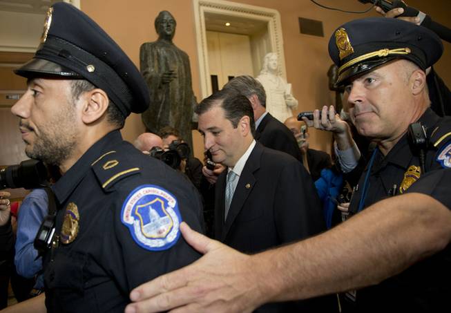 Sen. Ted Cruz, R-Texas, walks with security before talking to reporters on Capitol Hill, Wednesday, Oct. 16, 2013, in Washington. Sen. McConnell and his Democratic counterpart, Senate Majority Leader Harry Reid, D-Nev., are optimistic about forging an eleventh-hour bipartisan deal preventing a possible federal default and ending the partial government shutdown after Republican divisions forced GOP leaders to drop efforts to ram their own version through the House.