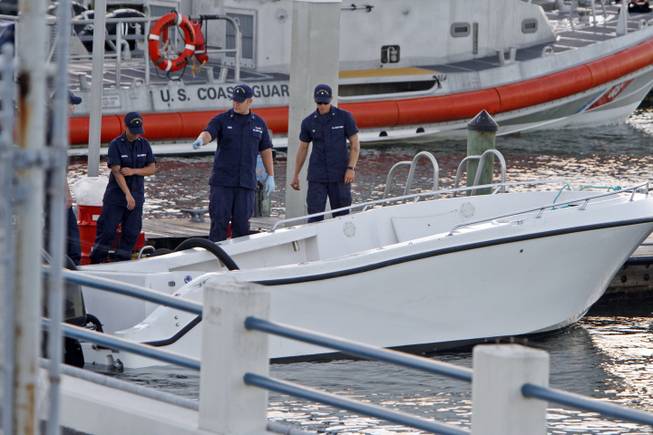 U.S Coast Guard personnel inspects a vessel with a missing center console that capsized near Miami, Wednesday Oct. 16, 2013. The Coast Guard responded to an early morning call and found nine people clinging to the hull seven miles east of Miami. Four women died and 10 other people were taken into custody after the boat with more than a dozen people aboard, including Haitian and Jamaican nationals, capsized in the waters off South Florida. Authorities are investigating whether the victims and survivors were part of a human smuggling operation.