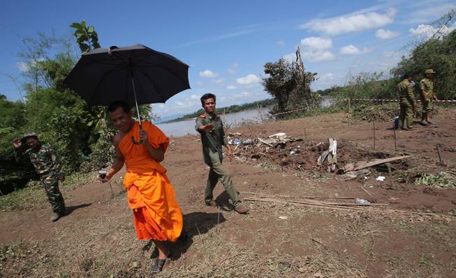 Lao soldiers ask a monk to leave from the crash site of a Laos Airlines plane in Pakse, Laos Thursday, Oct. 17, 2013. Rescuers in fishing boats pulled bodies from the muddy Mekong River on Thursday as officials in Laos ruled out finding survivors from a plane that crashed in stormy weather, killing 49 people from 11 countries.
