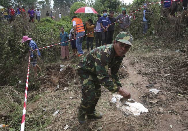 A Laos soldier works at the scene of the Laos Airlines plane crash in Pakse, Laos Thursday, Oct. 17, 2013. Rescuers in fishing boats pulled bodies from the muddy Mekong River on Thursday as officials in Laos ruled out finding survivors from the plane that crashed in stormy weather, killing 49 people from 11 countries.
