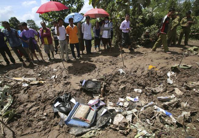 People look at the debris of a Lao Airlines turboprop plane that crashed into the Mekong River, in Pakse, Laos on Thursday, Oct. 17, 2013. Backpacks, an airplane propeller and passports were among the debris scattered on the riverbank where the Lao Airlines turboprop plane apparently hit hard before skidding into the water and sinking Wednesday, killing all 49 people onboard.