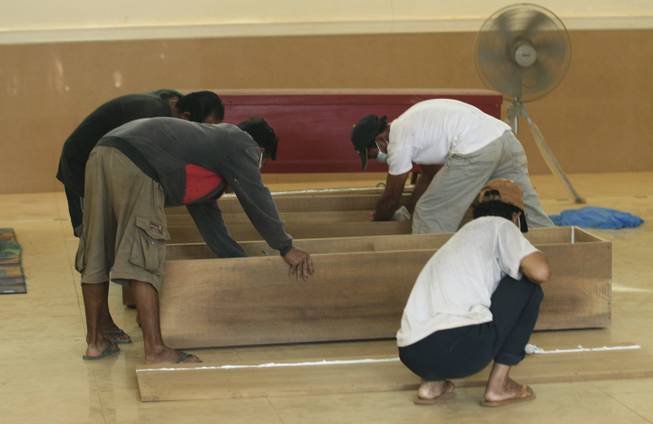 Workers prepare simple coffins at a Chinese temple in Pakse, Laos, Thursday, Oct. 17, 2013. The temple is being used as a temporary morgue for the victims of the Lao Airlines plane crash, though so far only a few have been found. The aircraft ran into extreme bad weather conditions and crashed into the Mekong River Wednesday, killing all 49 people onboard.