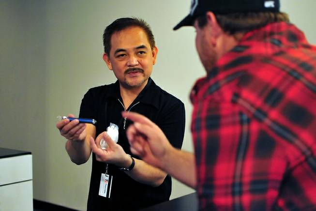 The Vapery owner Elmer John Yumul, 45, shows an e-cigarette to a customer at his vapor shop located at 8060 S. Rainbow Road, on Friday, Oct. 11, 2013. The rise in e-cigarette use among young adults and teenagers is a growing concern among health officials, who have long waged a public health campaign against smoking.