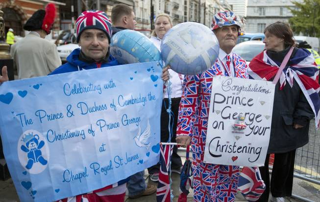 Royal wellwishers gather and display their home made placards and greetings to the media, as they wait outside St James's Palace, for the christening of Britain's Prince George, in London, Wednesday, Oct. 23, 2013. Prince William and his wife Kate have asked seven people to be godparents to their son, Prince George, who will be christened at a major royal family gathering Wednesday, palace officials said.