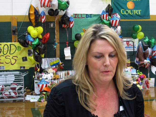 Katherine Loundon, the Washoe County School District's director of counseling, equity and diversity, talks with the media in front of a memorial to fallen teacher Michael Landsberry, that Sparks Middle School officials moved inside the gymnasium, on Thursday, Oct. 24, 2013, in Sparks, Nev. Students are to return to classes on Monday, a week after a 12-year-old gunman killed Landsberry and wounded two classmates before turning the gun on himself.