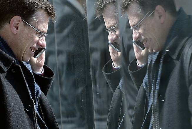 A man is reflected in paneling as he speaks on his phone at the Mobile World Congress, the world's largest mobile phone trade show, in Barcelona, Feb. 26, 2013. A Spanish newspaper published a document Monday that it said shows the U.S. National Security Agency spied on more than 60 million phone calls in Spain in one month alone.