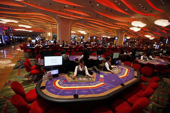 In this Sept. 20, 2012, file photo, croupiers sit at a baccarat gaming table inside a casino during the opening day of Sheraton Macao Hotel at the Sands Cotai Central in Macau. In China, the world’s largest gambling market, casino debts are not legally enforceable. Over the summer, a bilingual Chinese website posted a list of high rollers the site said were dodging their gambling debts.
