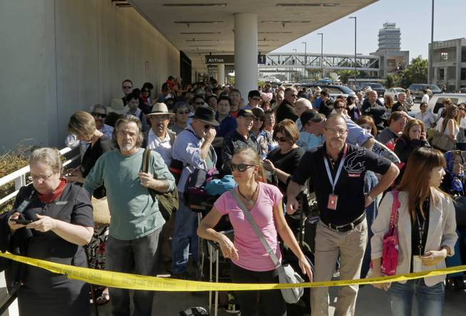 Passengers evacuated from Terminal 1 wait outside Los Angeles International Airport on Friday Nov. 1, 2013. Shots were fired Friday at Los Angeles International Airport, prompting authorities to evacuate a terminal and stop flights headed for the city from taking off from other airports.