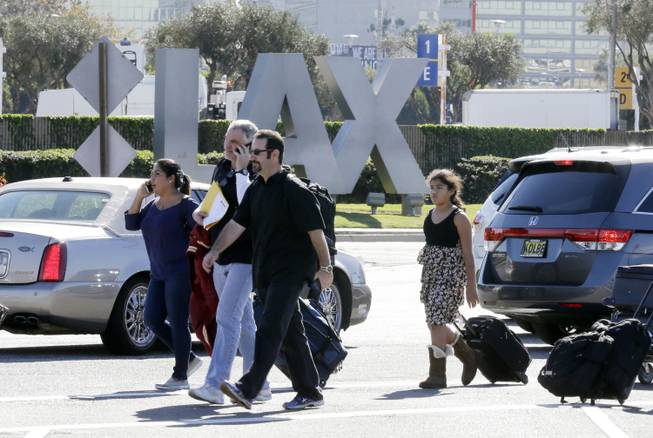 Passengers walk with their luggage while leaving Los Angeles International Airport on Friday Nov. 1, 2013. Shots were fired Friday at Los Angeles International Airport, prompting authorities to evacuate a terminal and stop flights headed for the city from taking off from other airports.