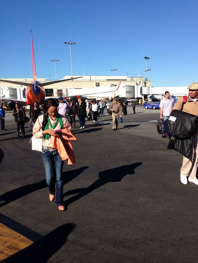 In this photo provided by Natalie Morin, people stand on the tarmac after being evacuated from Los Angeles International Airport, Friday, Nov. 1, 2013, after shots were fired at Terminal 3, prompting authorities to evacuate the terminal and stop flights headed for the city from taking off from other airports.
