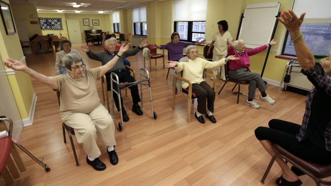 In this Oct. 4, 2013 photo, Holocaust survivor, Margie Oppenheimer, 89, left, participates in a yoga class with others at the retirement community called Selfhelp Home, on the North Side of Chicago. One day at the Stutthof concentration camp in Poland, Nazis marched Oppenheimer and others naked into an open field for inspection. Those strong enough to work were directed to the right. Oppenheimer, who was emaciated, was ordered to the left with hundreds of older women. She was placed into new barracks and had the Roman numeral II scrawled on her left forearm. Death seemed inevitable. "I'm thinking this is the last time I will see the sun," she recalls. (AP Photo/M. Spencer Green)
