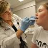 Photo: Dr. Laura Scalfano prepares to take a throat cultu Photo: Dr. Laura Scalfano prepares to take a throat cultu