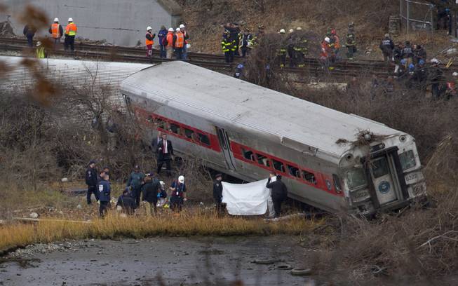 Viewed from Manhattan, first responders and others work at the scene of a derailed Metro North passenger train in the Bronx borough of New York Dec. 1, 2013. The train derailed on a curved section of track in the Bronx early Sunday, coming to rest just inches from the water, killing at least four people and injuring more than 60, authorities said. Police divers searched the waters to make sure no passenger had been thrown in, as other emergency crews scoured the surrounding woods.