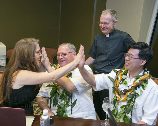 After having their marriage license approved by the state of Hawaii, Melissa Vomvoris, left, a licensed marriage agent, gives a high-five to couple Keola Akana, second from left, and Ethan Wung, right, as Rev. Brian Grieves looks on at the Sheraton Waikiki, Monday, Dec. 2, 2013 in Honolulu.