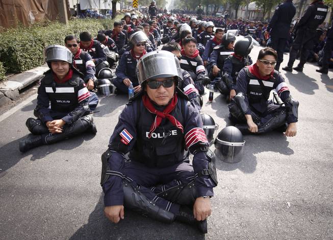 Thai riot police stand down outside the city police headquarters in Bangkok, Thailand, Tuesday, Dec. 3, 2013. Anti-government protesters crossed heavily fortified barriers and reached the gates of the Thai prime minister's office and the city police headquarters without resistance from police Tuesday.