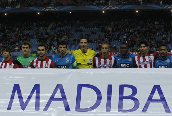 The referee, center, stands with Atletico and Porto players as they pose with a banner in support of former South African president Nelson Mandela, before the kick-off during a Group G Champions League soccer match between Atletico Madrid and FC Porto at the Vicente Calderon stadium in Madrid, Wednesday Dec. 11, 2013.
