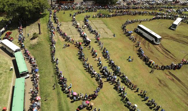 People queue to catch a bus to see the remains of Nelson Mandela at the Union Buildings in Pretoria, South Africa, Thursday, Dec. 12, 2013. The body of Nelson Mandela is being take in procession to the Union Buildings in Pretoria where it will lie in state for three days. Each morning his remains will be transported from the mortuary to the government buildings.