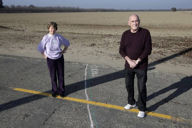 Phyllis and Ross Browning stand alongside a line drawn across Cairo Avenue marking the path of the proposed high-speed rail through their Hanford, Calif., neighborhood, Dec. 12, 2013. The proposed rail line will run a few houses away from their residence. The couple moved to Hanford in 2005 to retire and live next door to Phyllis' mother.