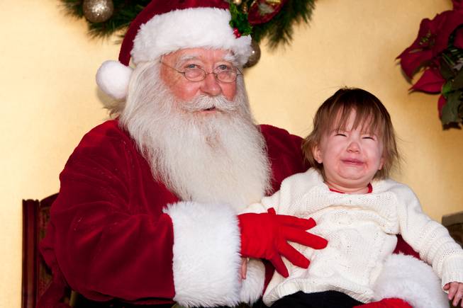 Fifteen-month-old Taylor Ireland bawls in the arms of Santa Claus while visiting him in his cottage at Tivoli Village in Las Vegas Friday, December 13, 2013. Larry Hansen has been donning the coveted suit and sharing the spirit of Santa for over nine years in Las Vegas.