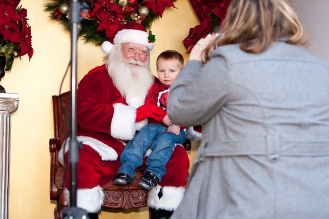 Landon Harrison, 2, looks a bit uneasy while his mom, Melissa, takes a photograph of him with Santa Claus in his cottage at Tivoli Village in Las Vegas Friday, December 13, 2013. Larry Hansen has been donning the coveted suit and sharing the spirit of Santa for over nine years in Las Vegas.