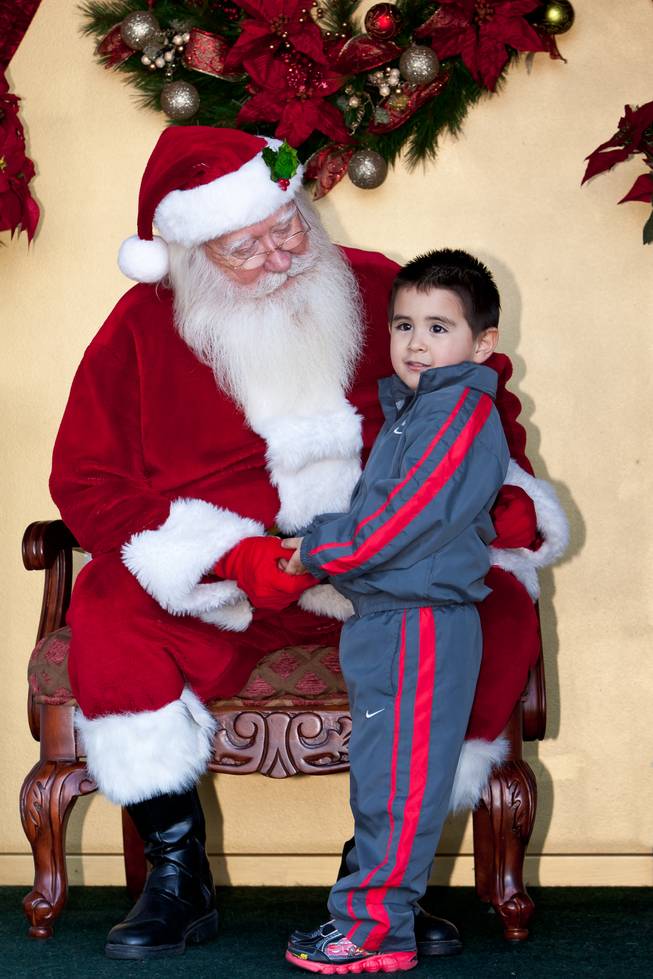 Santa Claus asks Matthew Trujillo, 3, what he wants for Christmas while visiting him in his cottage at Tivoli Village in Las Vegas Friday, December 13, 2013. Larry Hansen has been donning the coveted suit and sharing the spirit of Santa for over nine years in Las Vegas.