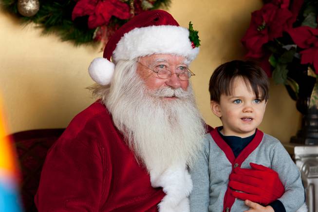 Two-year-old Bronson Frederick, who wants cars and trucks for Christmas, smiles for a photo with Santa Clause while visiting Santa in his cottage at Tivoli Village in Las Vegas Friday, December 13, 2013. Larry Hansen has been donning the coveted suit and sharing the spirit of Santa for over nine years in Las Vegas.